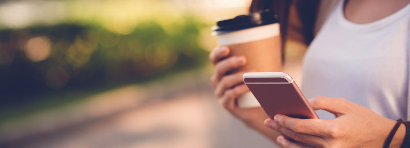 Woman holding phone and coffee.