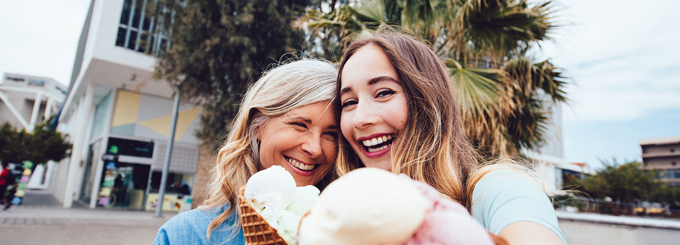 Mom and grown daughter take selfie with ice cream.