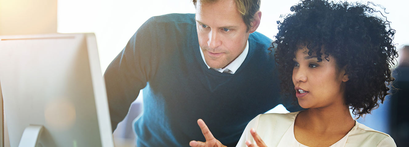 Coworkers discussing in front of computer.