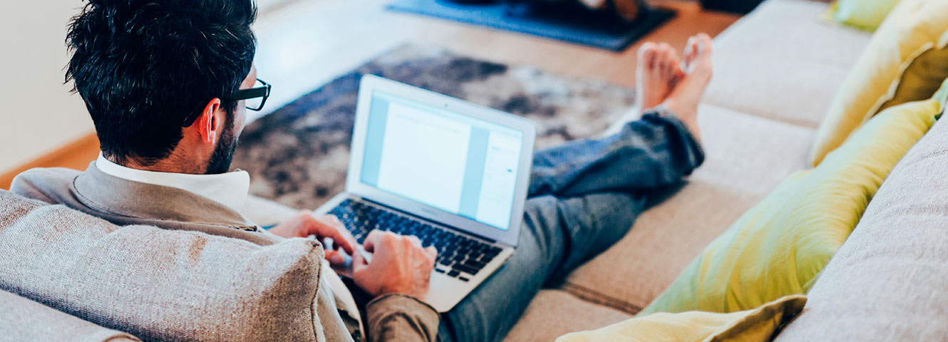 Man relaxing on couch with laptop.