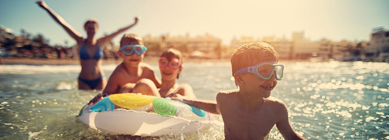 Three kids and mom swimming in lake.